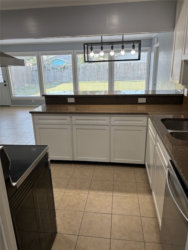 kitchen with white cabinets, light tile patterned flooring, hanging light fixtures, dishwasher, and dark stone countertops