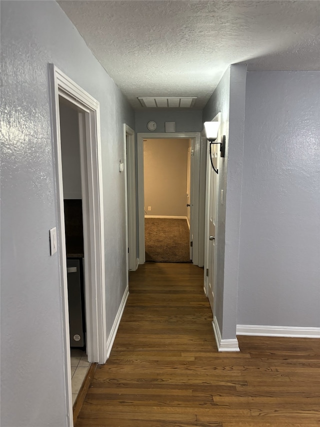 hallway with a textured ceiling and hardwood / wood-style floors