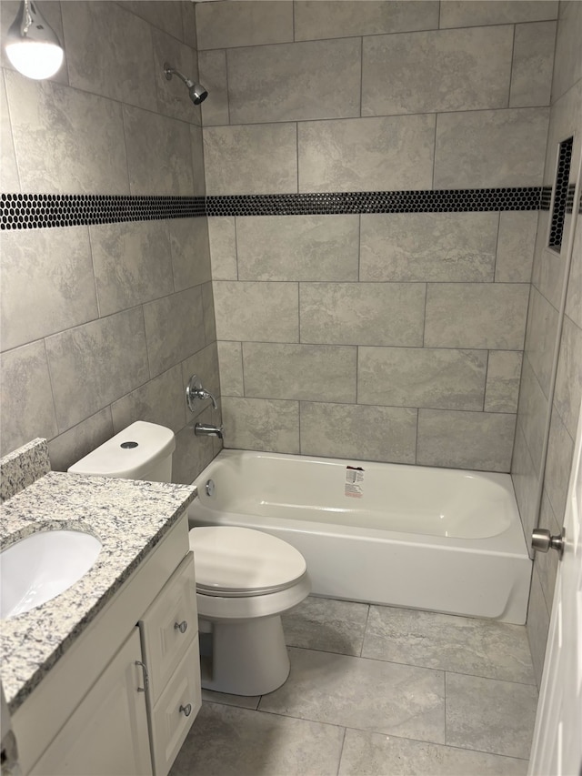 full bathroom featuring tiled shower / bath, vanity, tile walls, and toilet