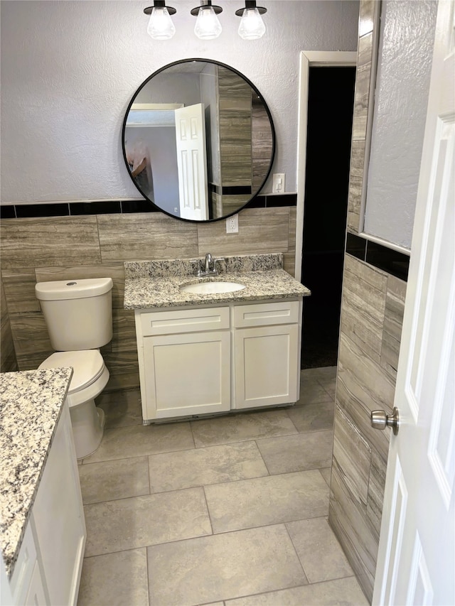 bathroom featuring tile walls, vanity, and toilet