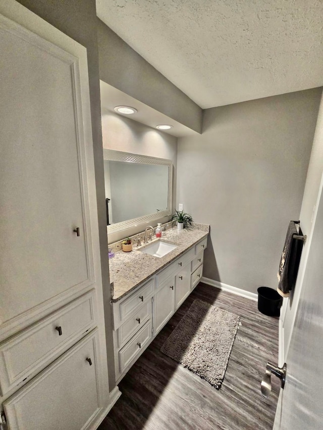 bathroom with wood-type flooring, a textured ceiling, and vanity