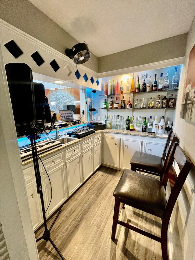 kitchen featuring white cabinets, a textured ceiling, light hardwood / wood-style flooring, and crown molding