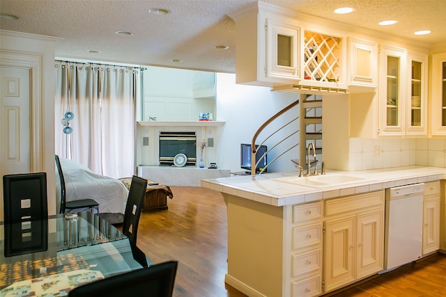 8235 Sands Point Dr Unit 156, Houston, TX 77036 - kitchen with dishwasher, tile counters, a textured ceiling, wood finished floors, and tasteful backsplash