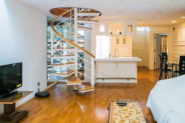 living room with wood-type flooring, a textured ceiling, crown molding, and sink