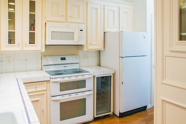 kitchen with tasteful backsplash, beverage cooler, light hardwood / wood-style flooring, white appliances, and tile countertops