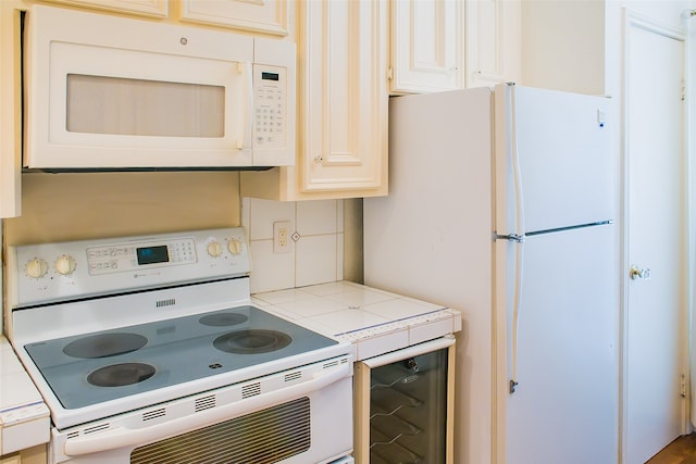 kitchen featuring tile countertops, backsplash, and white appliances