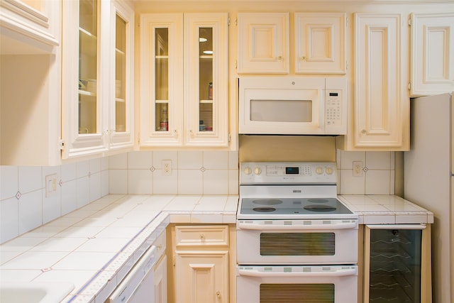 kitchen with wine cooler, tile countertops, backsplash, and white appliances