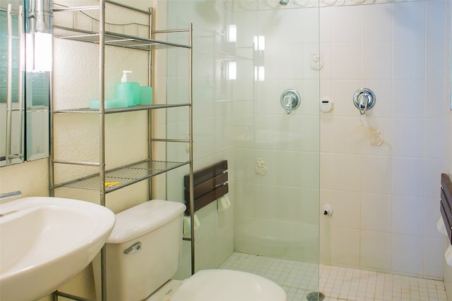 bathroom featuring a tile shower, sink, and toilet