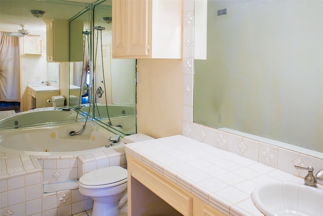 bathroom with ceiling fan, a relaxing tiled tub, vanity, and toilet