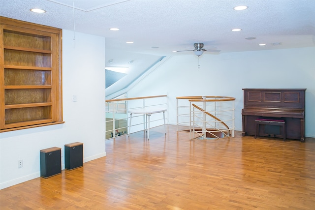 unfurnished living room featuring ceiling fan, hardwood / wood-style floors, and a textured ceiling