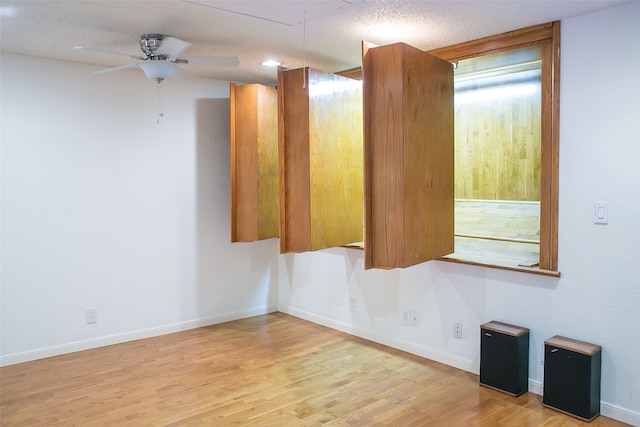 spare room with light wood-type flooring, ceiling fan, and a textured ceiling