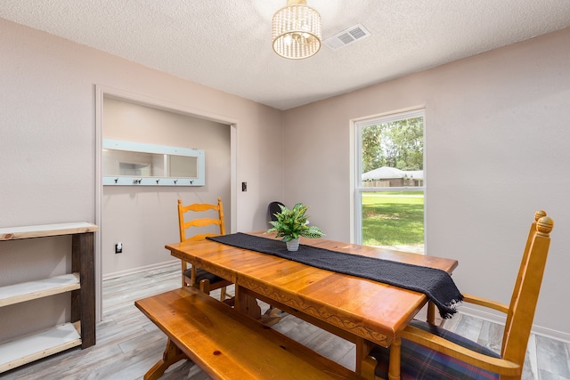 dining space featuring a chandelier, a textured ceiling, and light wood-type flooring