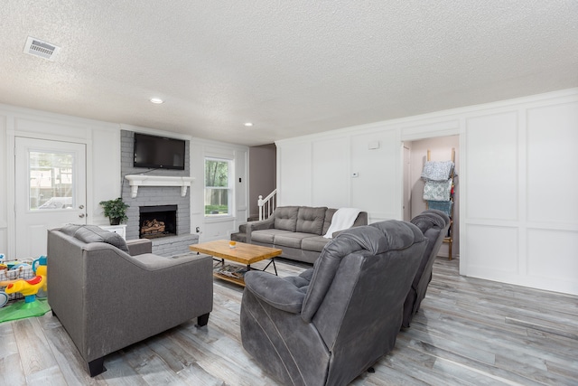 living room featuring a textured ceiling, a fireplace, and light wood-type flooring