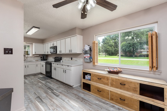 kitchen featuring ceiling fan, white cabinetry, light wood-type flooring, black appliances, and sink