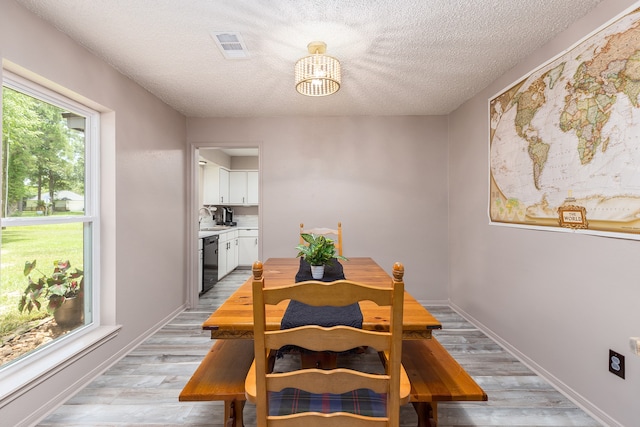 dining space featuring light hardwood / wood-style flooring, a textured ceiling, a chandelier, and sink