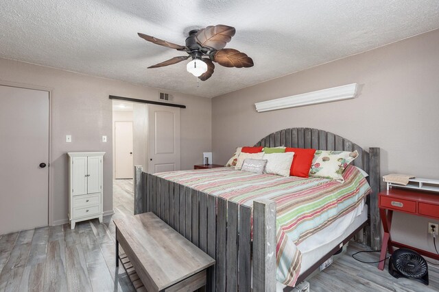 bedroom with light hardwood / wood-style floors, a textured ceiling, and ceiling fan