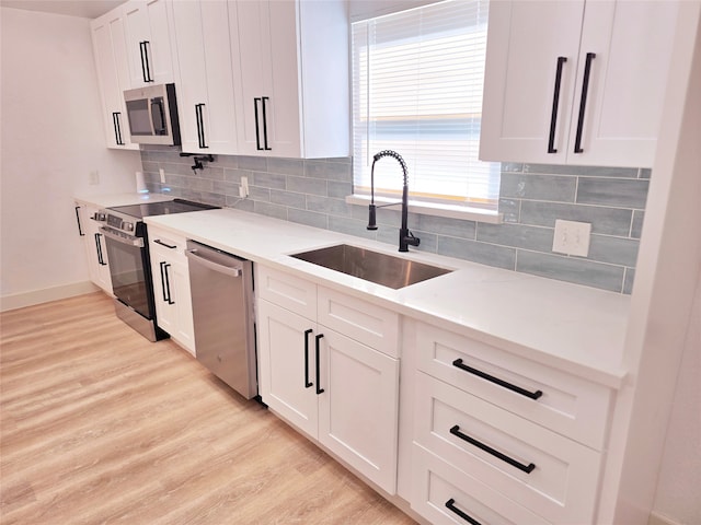 kitchen featuring white cabinets, light wood-type flooring, stainless steel appliances, and sink