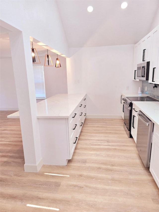 kitchen with lofted ceiling, white cabinets, light stone countertops, and stainless steel appliances