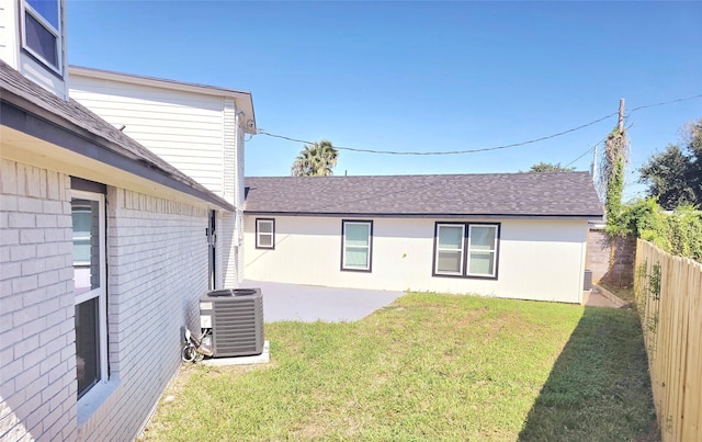 back of house with central AC, a patio, and a lawn