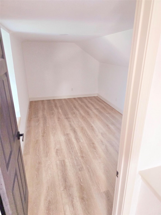 unfurnished room featuring light wood-type flooring and vaulted ceiling