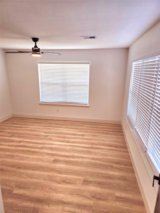 spare room with light hardwood / wood-style floors, a wealth of natural light, and ceiling fan