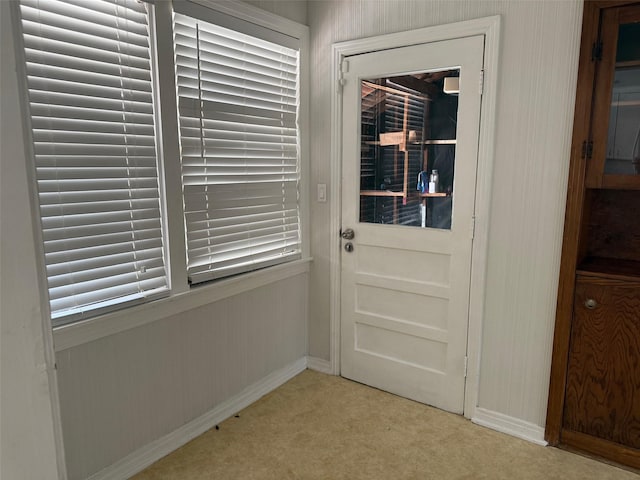 doorway featuring light carpet and baseboards