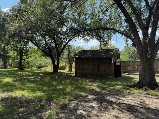 view of yard featuring an outdoor structure, a shed, and fence