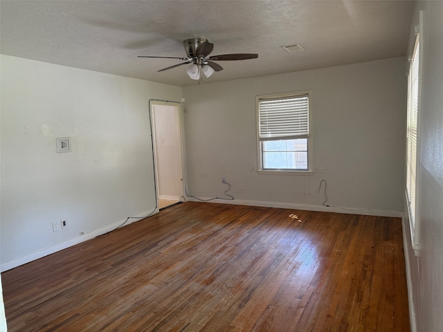 empty room featuring ceiling fan, dark wood-type flooring, and a textured ceiling