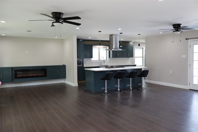 kitchen featuring island exhaust hood, a kitchen breakfast bar, dark wood-type flooring, decorative light fixtures, and a center island