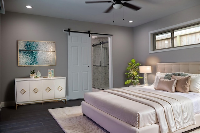 bedroom featuring dark hardwood / wood-style flooring, a barn door, and ceiling fan