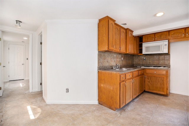 kitchen with tasteful backsplash, sink, stainless steel gas stovetop, light tile patterned floors, and crown molding