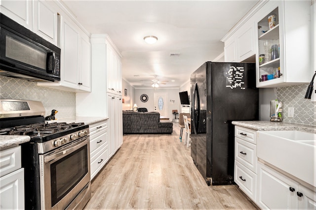 kitchen featuring light hardwood / wood-style floors, white cabinets, decorative backsplash, black appliances, and ceiling fan