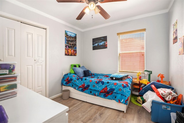 bedroom featuring crown molding, light hardwood / wood-style flooring, ceiling fan, and a closet