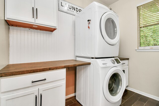 clothes washing area featuring dark hardwood / wood-style flooring, cabinets, and stacked washer / drying machine