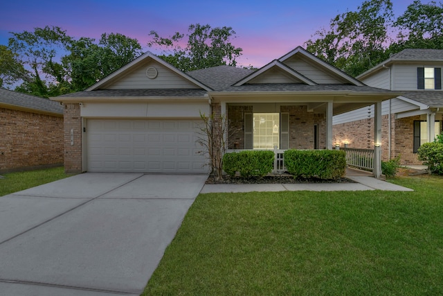 view of front of house featuring a garage, covered porch, and a yard