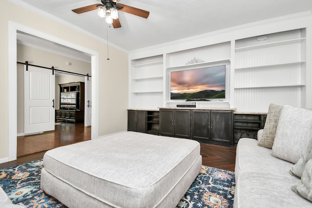 living room featuring dark parquet flooring, ornamental molding, built in shelves, ceiling fan, and a barn door