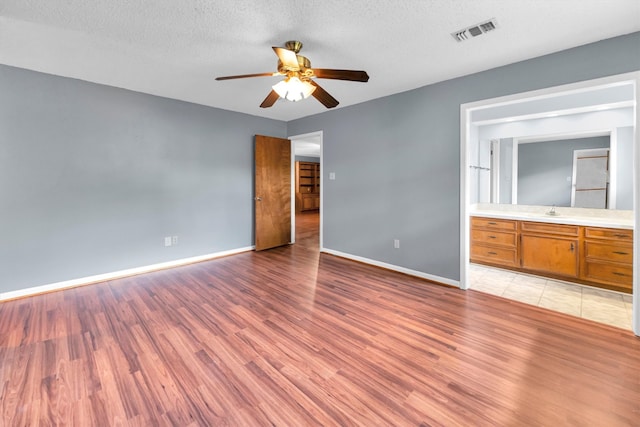 unfurnished living room featuring ceiling fan, a textured ceiling, light wood-type flooring, and sink