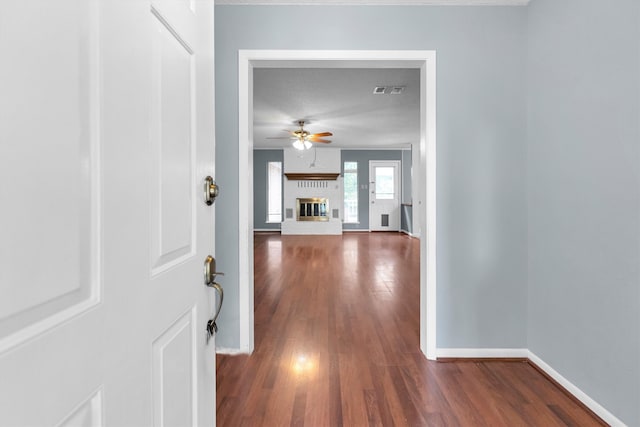 entryway with a brick fireplace, dark hardwood / wood-style flooring, and ceiling fan