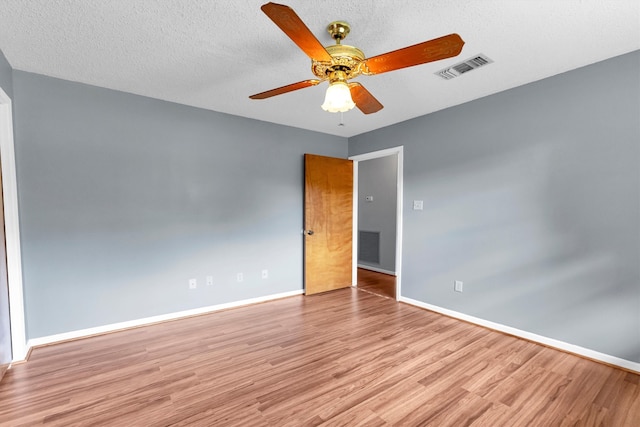 empty room with ceiling fan, a textured ceiling, and light wood-type flooring