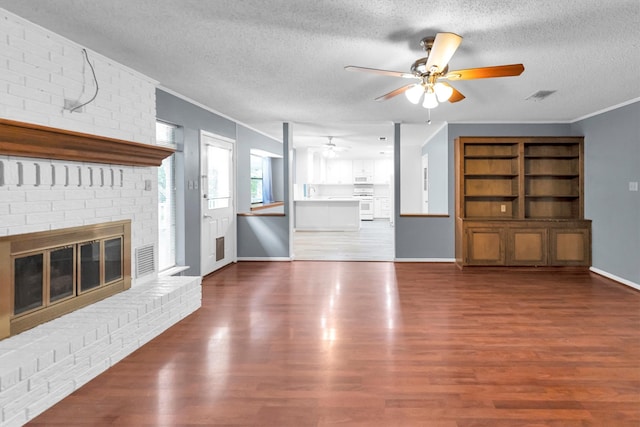 unfurnished living room featuring ceiling fan, a textured ceiling, a fireplace, and hardwood / wood-style floors