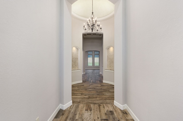 hall with a notable chandelier and wood-type flooring