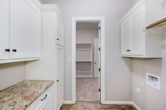 washroom with wood-type flooring, washer hookup, and cabinets