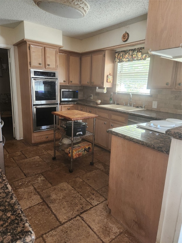 kitchen featuring backsplash, sink, a textured ceiling, and appliances with stainless steel finishes