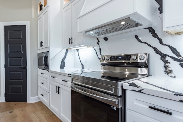 kitchen featuring premium range hood, white cabinetry, light hardwood / wood-style flooring, and stainless steel appliances