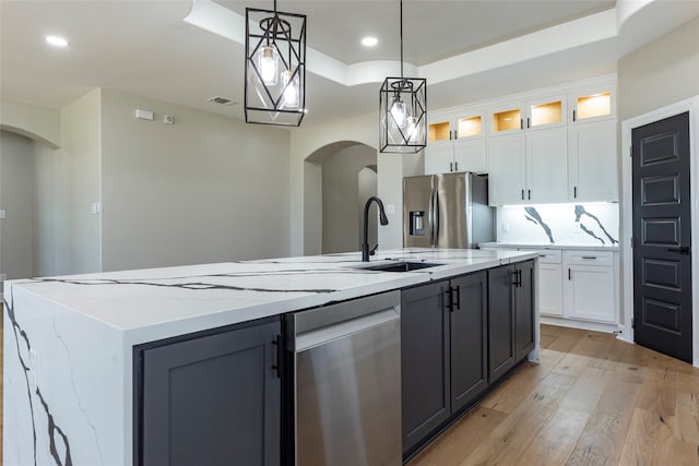 kitchen featuring pendant lighting, white cabinets, a center island with sink, light hardwood / wood-style flooring, and stainless steel appliances