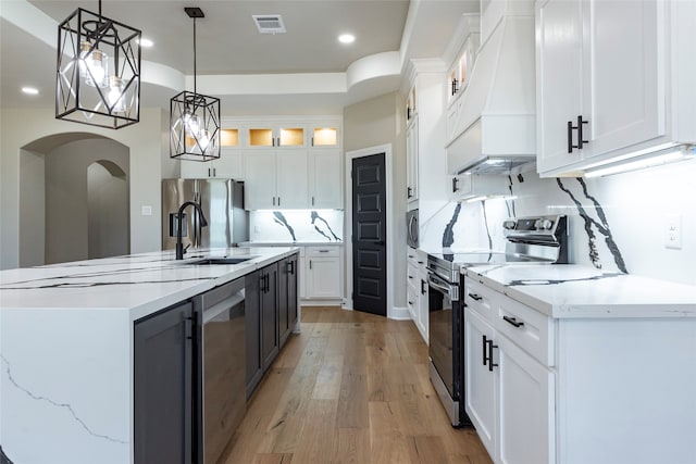 kitchen featuring appliances with stainless steel finishes, white cabinetry, and decorative light fixtures