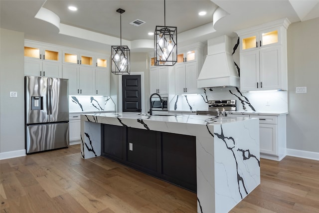 kitchen with stainless steel appliances, sink, a large island with sink, and premium range hood