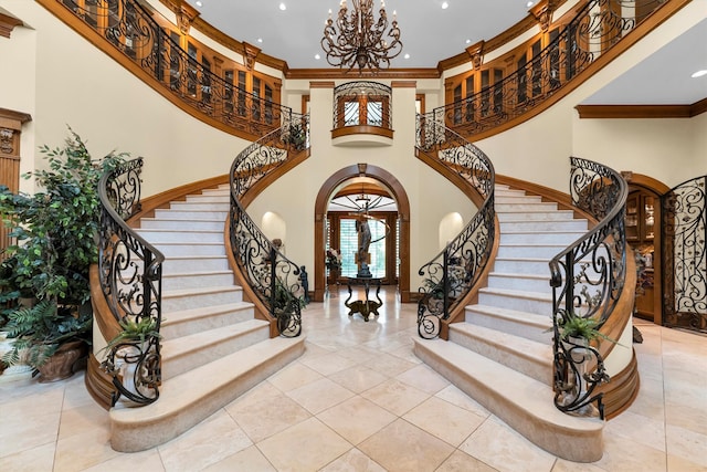 foyer with ornamental molding, a high ceiling, light tile patterned flooring, and an inviting chandelier