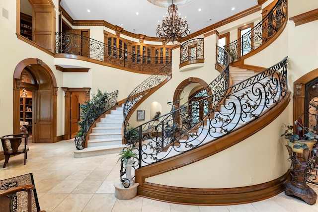 staircase with a notable chandelier, a towering ceiling, tile patterned flooring, and crown molding