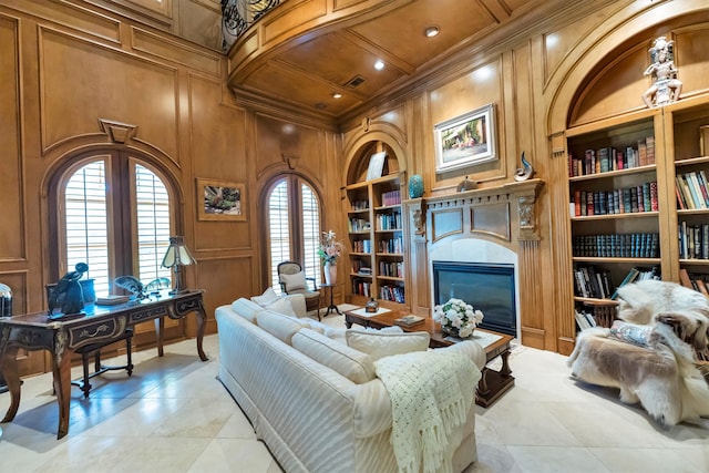 sitting room with built in shelves, wood walls, and crown molding